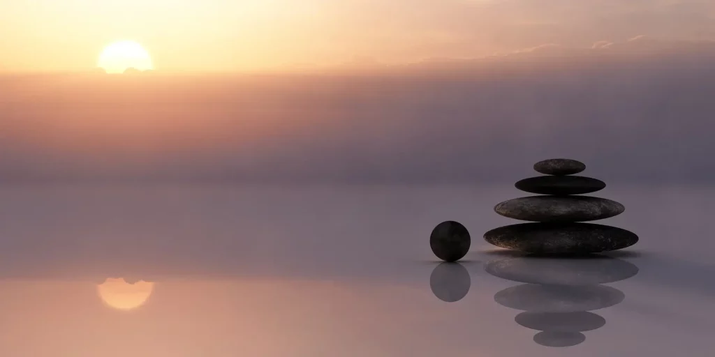 Découvrez cette image apaisante : un empilement de pierres, équilibrées avec harmonie, sous un coucher de soleil. L'évocation du côté zen et calme de cette scène invite à un voyage intérieur. Explorez la sérénité à travers cette représentation, ouvrant la porte à une introspection profonde.