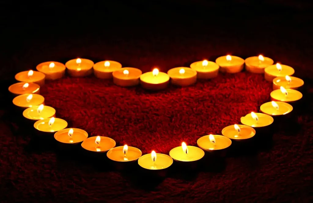 Découvrez cette image émouvante : des bougies disposées en forme de cœur, symbolisant l'amour qui persiste au-delà de l'absence. Explorez la beauté de cette représentation qui transcende la distance physique, évoquant un amour qui brille même dans l'obscurité.