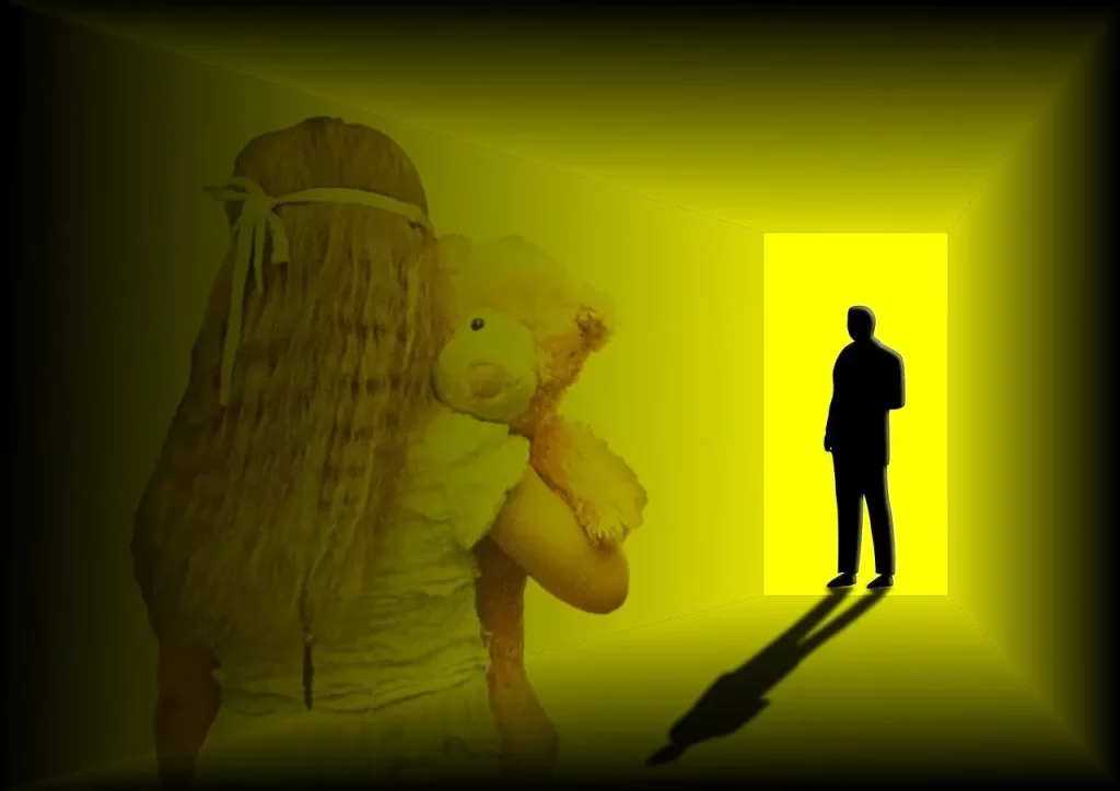 Dans un décor obscur, une fillette solitaire tient son nounours bien serré dans ses bras, une lueur de vulnérabilité dans son dos. À l'arrière-plan, un encadrement éclairé dans les tons jaunes attire l'attention, mais ce qui se dessine à travers lui est loin d'être rassurant : une silhouette masculine dont l'ombre s'étend menaçante vers la fillette. Cette image poignante évoque les origines sombres du schéma «Méfiance et Abus», où l'enfance devient le théâtre de traumatismes invisibles qui laisseront des cicatrices émotionnelles durables.
