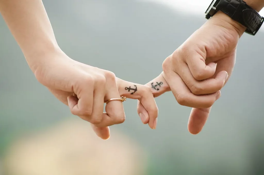 La connexion intime entre deux âmes, symbolisée par leurs doigts entrelacés, révèle un lien profond forgé dans l'amour et la confiance. Malgré les tourments du passé, leurs cœurs trouvent refuge dans cette union, où chaque tatouage raconte une histoire d'affection éternelle. Dans un monde d'incertitudes, ils se tiennent mutuellement, surmontant ensemble les défis du présent pour construire un avenir solide et harmonieux.