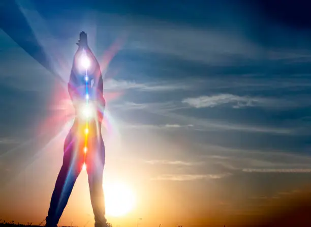 Explorez la transcendance à travers notre image captivante : la silhouette d'une personne baignée de lumière, avec ses chakras visibles, symbolisant l'âme qui entre dans l'au-delà. Chaque centre énergétique vibrant, chaque rayon de lumière, témoigne de la transition spirituelle de cette âme. Plongez dans l'instant sacré où la personne se libère pour rejoindre les horizons infinis de l'au-delà, illuminée par la sérénité et la transcendance.