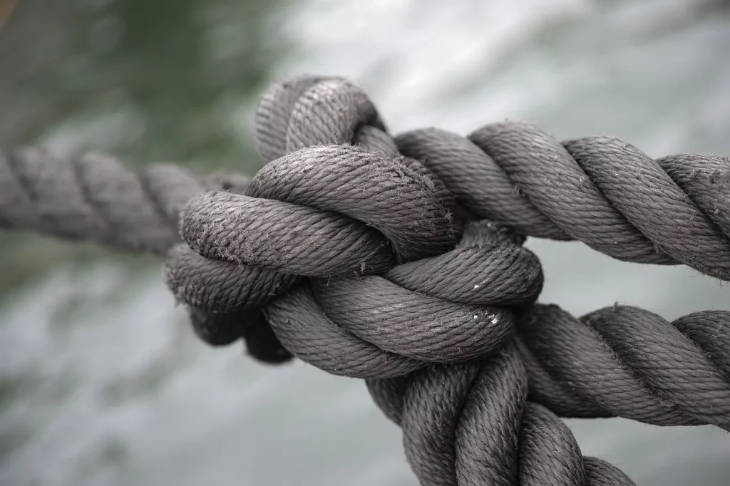 La photo d'une corde nouée symbolise les liens complexes de la dépendance. Chaque nœud représente un obstacle à surmonter dans la quête d'autonomie. Tout comme défaire les nœuds de cette corde demande patience et persévérance, briser le schéma de dépendance nécessite un effort continu et une volonté de progresser vers une vie plus autonome.